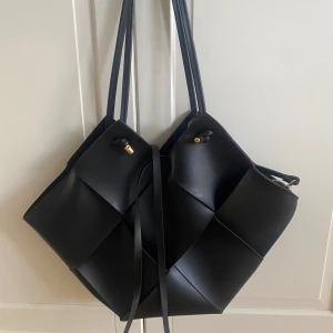 Svart axelväska från Bottega Veneta - Helt ny svart axelväska likt Bottega Veneta, flätad med  gulddetaljer. Väskan har långa axelband och medföljer en matchande innerpouch med dragkedja. 