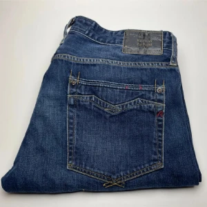 Replay Newbill blå jeans herr - Säljer ett par klassiska Replay Newbill jeans i mörkblå denim. Snygga kontrastsömmar, femficksmodell och diskret Replay-logga på bakfickan. Perfekta för dig som gillar en tidlös och avslappnad look.