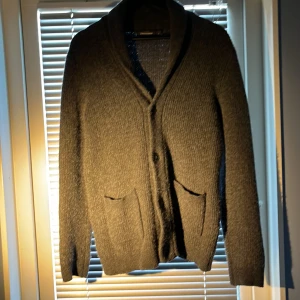 M men sitter som S pga tvätt  - Mysig grå kofta från Dressmann i stickad ullmix. Koftan har två fickor framtill, knäppning med knappar och en klassisk krage. Perfekt för lager-på-lager och chill höst- eller vinterstil.