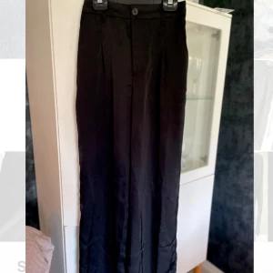 Svarta vida kostymbyxor Divided XS - Supersnygga svarta tunna kostymbyxor/finbyxor från Divided (H&M) storlek XS. Byxorna har hög midja, vida ben. Tillverkade i ett mjukt polyestertyg som ger en dressad känsla. Perfekta för dig som gillar stilrena och trendiga plagg. Använda endast vid ett tillfälle, därav helt nytt skick. 