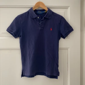 Marinblå pikétröja från Polo Ralph Lauren barn/kille - Snygg marinblå pikétröja från Polo Ralph Lauren i slim fit-modell. För barn/kille. Storlek M (10-12)