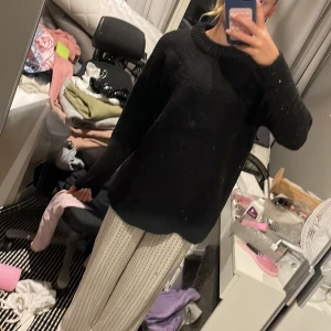 Svart stickad tröja med rund hals - Mysig svart stickad tröja med rund halsringning och ribbade muddar. Tröjan har en loose passform och långa ärmar, perfekt för kyliga dagar. Enkel och stilren design som funkar till det mesta. Snygg att matcha med jeans eller mjukisbyxor. Tjockt material.