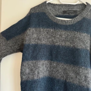 Randig tröja från Graumann - Säljer en mysig randig tröja från Graumann i blått och grått. Tröjan har en normal passform och är långärmad, perfekt för kyligare dagar. Den är tillverkad i ett mjukt material som känns skönt mot huden.