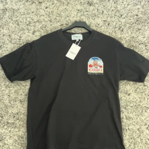 Svart t-shirt från Casablanca - Snygg svart t-shirt från Casablanca med ett färgglatt tryck av en byggnad och texten 'casa' på både fram- och baksidan. Perfekt för en avslappnad stil med en touch av färg.