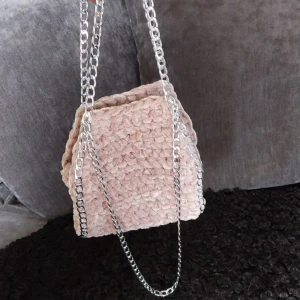 Rosa virkad väska med kedja - Snygg rosa väska med en stilren silverfärgad kedja. Perfekt för att ge din outfit en unik touch. Väskan har en mjuk och mysig textur.