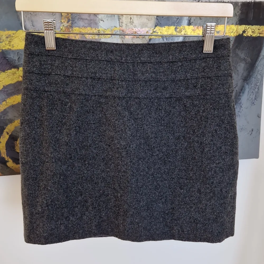 Snygg grå kjol från H&M i en klassisk stil. Kjolen har en kort längd och en diskret dragkedja i sidan för enkel påklädning. Perfekt för en stilren look.. Hameet.