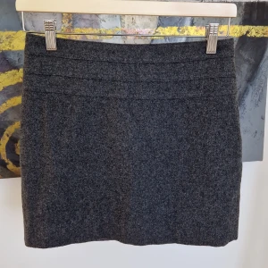 Grå kjol från H&M - Snygg grå kjol från H&M i en klassisk stil. Kjolen har en kort längd och en diskret dragkedja i sidan för enkel påklädning. Perfekt för en stilren look.