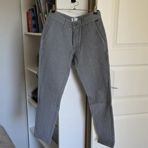 Grå kostymbyxor - Snygga grå kostymbyxor med normal passform och midwaist. Byxorna har knappar och dragkedja framtill samt fickor både fram och bak. Perfekta för en stilren look.