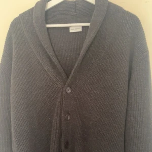 Cardigan  - En stilren John henric cardigan i mörkgrå färg, finns ej att köpa mer. Använd endast 2 gånger, är som ny. Finns inga defekter alls. Hör av er vid frågor!
