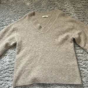 Stickad tröja från Gina - slutsåld - Säljer en stilren beige stickad tröja från Gina Tricot i storlek S. Tröjan har en v-ringad design och ribbade detaljer vid hals och nederkant. Perfekt för kyligare dagar och enkel att matcha med olika outfits. Ordinarie pris 700kr denna finns inte längre att köpa hos Gina