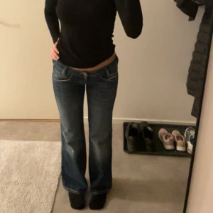 Mörkblåa Diesel jeans - Snygga mörkblå, lågmidjade, bootcut jeans från Diesel med unika broderade detaljer på bakfickorna. Jeansen har en klassisk femficksdesign och kontrastsömmar i rött. Perfekta för en stilren look. Står storlek 29/32 men jag själv är st 27-28 i midjan och de är för små så skulle säga att de sitter som 26/32 istället. Priset kan diskuteras vid snabb affär & skriv jättegärna vid frågor eller funderingar!💞