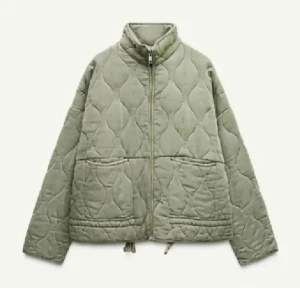 Grön quiltad jacka - Säljer en stilren grön quiltad jacka med dragkedja och hög krage. Jackan har en loose passform och praktiska fickor framtill. Perfekt för kyligare dagar.