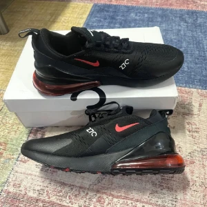 Nike Air Max 270 i svart och röd - Säljer ett par stilrena Nike Air Max 270 sneakers i svart med röda detaljer. Skorna har en synlig Air Max-enhet i hälen och en bekväm passform med snörning. Perfekta för både träning och vardag.