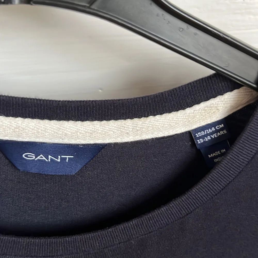 Snygg svart t-shirt från GANT med stort vitt tryck på framsidan. Perfekt för en avslappnad stil. Tillverkad i mjukt material för extra komfort. Passar både till jeans och shorts!. T-paidat.