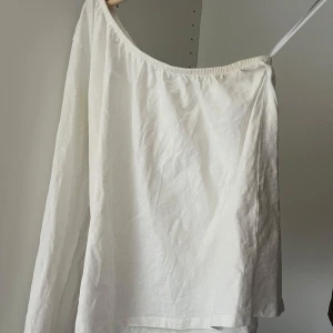 Vit oneshoulder-topp - Säljer min vita oneshoulder-topp med lång ärm från Mango 