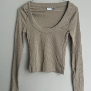 Beige ribbad topp från ASOS DESIGN - Säljer en stilren beige ribbad topp från ASOS DESIGN. Toppen har en rundad halsringning och långa ärmar, perfekt för lager-på-lager eller som den är. Enkelt att matcha med olika outfits.