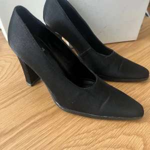 Vintage! Svarta pumps från Attention - Eleganta svarta pumps från Attention med spetsig tå och klack. Perfekta för en stilren look. Tillverkade i ett glansigt material som ger en lyxig känsla.