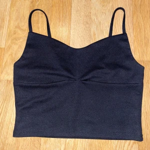 Svart linnetopp - Snygg svart linnetopp med smala axelband och en enkel design. Perfekt för en stilren look.