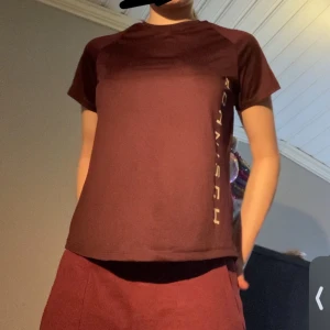 Tränings tröja  - Säljer en vinröd t-shirt från Röhnisch med tryck på sidan. Perfekt för en sportig look eller avslappnad stil. Tillverkad i ett mjukt och bekvämt material. Osäker på om jag vill sälja 