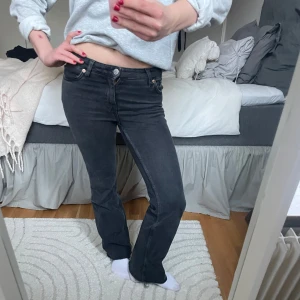 Low waist bootcut jeans - Snygga svarta bootcut jeans med låg midja. Perfekta för en avslappnad stil. De har en klassisk femficksdesign och knappar i midjan. Passar bra till både sneakers och klackar.