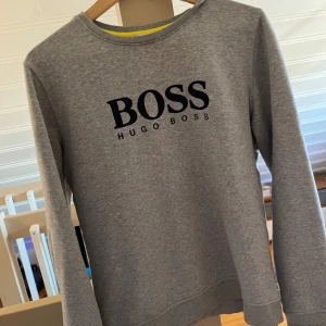 Grå Hugo Boss tröja - Väldigt bra skick, använt ett få antal gånger. Har två gula fläckar på högra armen men syns knappast när tröjan är på.