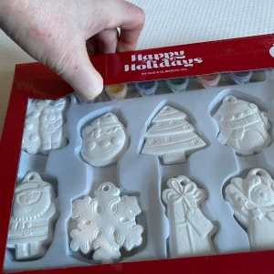 Målarset med juldekorationer - Säljer ett målarset med vita juldekorationer i olika former som snögubbe, julgran och snöflinga. Setet innehåller även färger och en pensel för att dekorera figurerna. Perfekt för att skapa personliga julprydnader! 🎨🎄