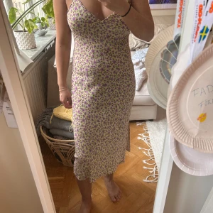 Gul midiklänning från Zara  med slits stl M - Säljer en söt midiklänning med blommigt mönster och gul bas. Klänningen har smala axelband och en v-ringad halslinje. Den har en slits på sidan som ger en fin detalj. Perfekt för sommarens varma dagar! Köpt secondhand och enbart provad av mig. Jag är cirka 163 cm och väger 65 kg. Inget att anmärka på
