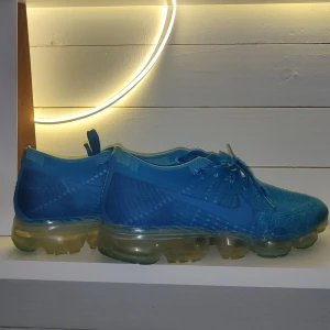 Nike Vapormax skor  - Jättefina blåa Vapormax skor i storlek 42. Köpte dom för inte längesen men knappt använt eftersom jag inte hade kläder som passade till färgen, därför väljer jag att sälja dem. Pris kan diskuteras !! Nypris 1400.