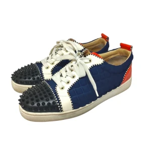 Christian Louboutin Färgglada sneakers med nitar - Unika sneakers med en mix av blått, vitt och rött. Skorna har en quiltad textur och är dekorerade med svarta nitar på tån. De har vita snören och en röd sula med ett mönster. Perfekta för dig som vill sticka ut!