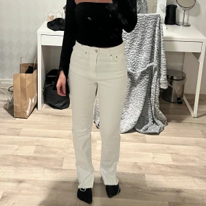Vita raka jeansbyxor med slits - Säljer ett par vita jeansbyxor med rak passform och hög midja. 