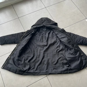 Svart lång dunjacka med huva - Säljer en svart lång dunjacka med huva,.