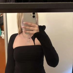 Svart långärmad klänning med fyrkantig urringning - Säljer en svart, tight långärmad klänning med snygg fyrkantig urringning. Klänningen är enkel och stilren, perfekt att styla med smycken eller boots. Materialet känns stretchigt och följsamt.