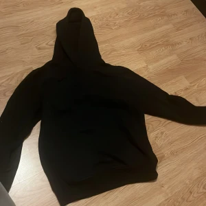 Svart hoodie med Ice Cube-tryck använd 1 gång - Svart hoodie med stort tryck på ryggen föreställande Ice Cube och texten 'Today Was A Good Day'. Klassisk modell med huva och känguruficka framtill. Perfekt för dig som gillar streetwear och hiphop.