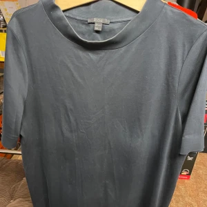 Svart t-shirt från COS - En stilren svart t-shirt från COS med rund halsringning och korta ärmar. Tillverkad i ett mjukt material som känns skönt mot huden. Perfekt för en enkel och clean look.