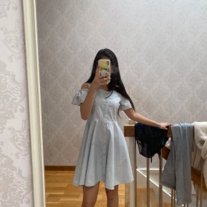 Ljusblå axelbandslös klänning  - Supersöt ljusblå klänning från Oh Hey med offshoulder och kort ärm. Klänningen har knappar längs hela framsidan. Perfekt för sommarens alla tillfällen!