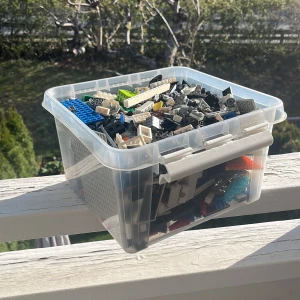 Stor låda med blandade LEGO-bitar - Säljer en plastlåda fylld med blandade LEGO-bitar i olika färger och former. Innehåller hjul, plattor, klossar och specialdelar i svart, vitt, blått, grönt och grått. Perfekt för dig som vill bygga egna LEGO-kreationer eller fylla på samlingen.