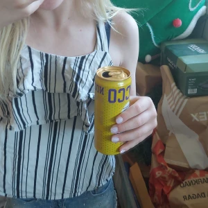  Jättesöt Vit och svart randig blus med volang - Säljer en söt blus med svarta ränder på vit botten och volangdetaljer framtill. Toppen har smala axelband och en luftig passform, perfekt för varma dagar.