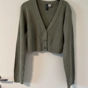 Grön ribbad croppad kofta från hm  - Säljer en grön ribbad kofta från HM. Tröjan är croppad med v-ringning och knappar.