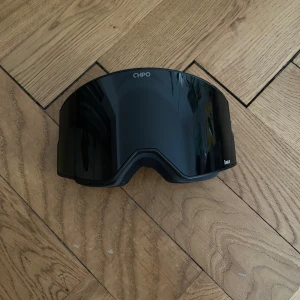 Svarta skidglasögon från CHPO - Helt nya och oanvända nypris är 1 800kr.inga defekter😊Säljer ett par svarta skidglasögon från CHPO med utbytbara linser. Ena linsen är mörk, den andra är orangefärgad. Bred svart rem med vit björnlogga på sidan. Perfekta för vinterns äventyr i backen.