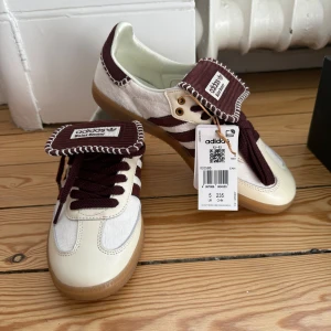 Adidas Wales Bonner Samba sneakers - Säljer ett par oanvända (taggen kvsr) limited edition Adidas Samba Wales Bonner sneakers i vitt och vinrött med detaljer i vit pony och de klassiska ränderna och kontrastsömmar. Skorna har gummisula, snörning och unika detaljer på plösen. Kommer med extra skosnören och originalpåse.