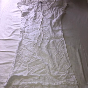 Vit klänning med volang från Flash - Säljer en vit klänning från Flash med volangdetaljer längst ner och knytband vid halsen. 