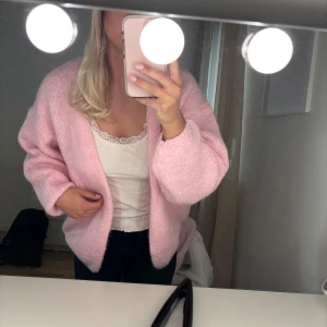 Ljusrosa stickad kofta - Supermjuk och fluffig ljusrosa stickad kofta från Lindex. Koftan har en avslappnad passform med långa ärmar. Perfekt att slänga över en topp för en mysig look. Helt oanvänd prislappen kvar!