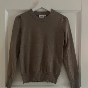 Brun stickad tröja  - Snygg brun stickad tröja från Saint Tropez i storlek XS. Tröjan har rund halsringning, ribbade muddar och långa ärmar med lätt puff vid axlarna. Knappt använd och i väldigt bra skick