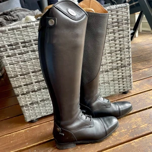 Svarta ridstövlar CRW Panaro - Aldrig använda! Ridstövel i mjukt läder med elastisk snörning och skinnfodrad insida. Grip-läder på insidan av skaftet. Resår utmed dragkedjan. Nypris 2399kr