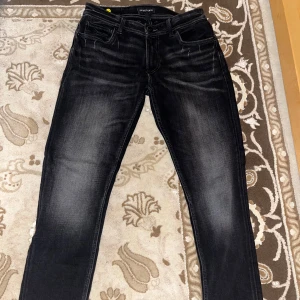 Svarta Jeans - Snygga svarta jeans från Smog Denim med slitna detaljer och tvättad look. Klassisk femficksmodell med raka ben och normal passform. Jeansen har tydliga kontrastsömmar och är tillverkade i ett mjukt jeanstyg som sitter skönt hela dagen.