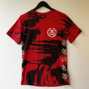 Stüssy Painted Tee All Over Print T-Shirt S - T-shirt med ett rött och svart mönster och Stüssy-logotyp på bröstet, ryggen och sidorna.   Storlek: S  Armhåla till armhåla: 44 cm  Längd: 67 cm   Använt men fint skick!   Sökord:  Brush strokes, create logo, Stussy, tee, tshirt.
