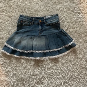 Jeanskjol med volanger och spets - En jeanskjol omsydd från ett par jeans. Midjemått tvärsöver - ca 32cm stretchig Längd - 35cm