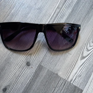 Raybans boyfriend liknande  - Snygga solglasögon med svart, glansig båge och rektangulär form. Glasen är lila tonade och ger en cool vibe. Perfekta för att lyfta din stil under soliga dagar. Lätta och bekväma att bära. Helt nya