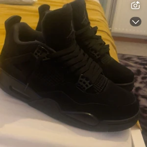 Svarta Nike Jordan 4 sneakers - Säljer ett par helsvarta Nike Jordan 4 sneakers med klassisk siluett och coola meshdetaljer på sidorna. Skorna har snörning, hög profil och är tillverkade i en mix av mocka och syntet. Perfekta för dig som vill ha en clean och stilren look.