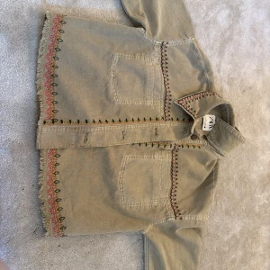 Beige broderad overshirt från Zara - Säljer en beige overshirt från Zara med broderade detaljer i rosa, svart och grönt längs krage, ärmslut och nederkant. 🌸😍